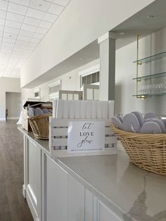 an empty room with white cabinets and baskets on the counter, in front of a sign that says eat love flour