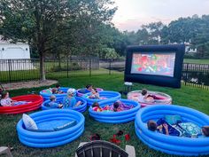 children are playing in an inflatable pool on the lawn