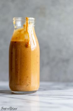 a glass jar filled with liquid sitting on top of a white marble counter next to a gray wall