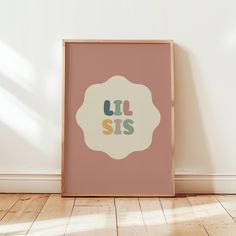 a pink poster with the words lil sis in multicolored letters on it against a white wall