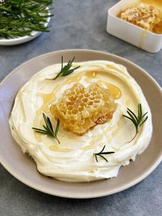 a plate topped with whipped cream and honey on top of a table next to a bowl of dip