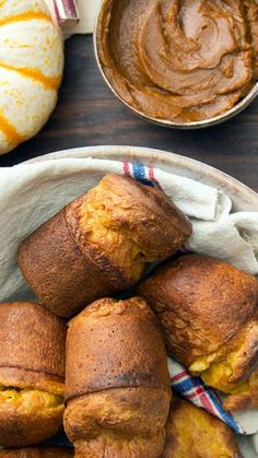 several pastries in a white bowl on a table with pumpkins and other food