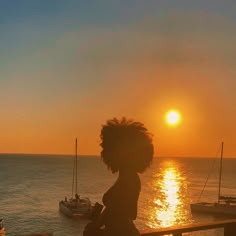 a woman sitting on a bench watching the sun set