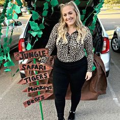 a woman standing in front of a car holding a sign that says jungle safari tigers monkeys bears