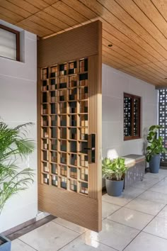 a wooden door in the middle of a room with potted plants on either side