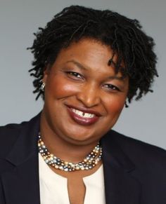 a woman wearing a suit and smiling at the camera with a necklace on her neck