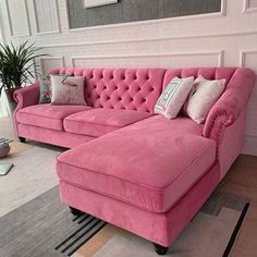 a living room with pink couches and pillows on the floor next to a rug