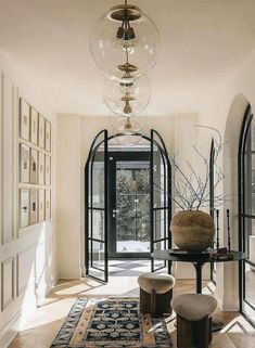 a hallway with an area rug, two stools and a large glass ball hanging from the ceiling