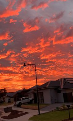 the sun is setting over some houses and cars