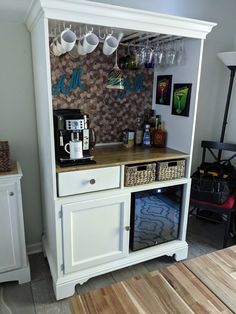 a coffee bar with cups hanging on the wall above it and an open drawer underneath