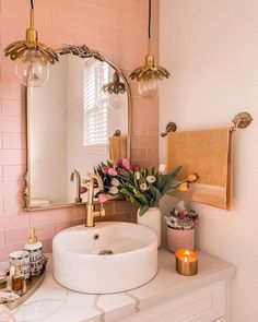 a white sink sitting under a bathroom mirror next to a pink tiled wall with flowers on it