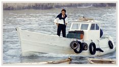 a man standing on top of a white boat in the middle of some water with other boats behind him