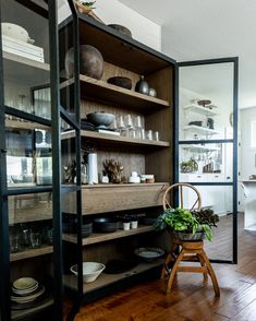 a wooden chair sitting in front of a shelf filled with dishes