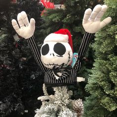 a fake skeleton in a santa hat on top of a christmas tree with his hands up