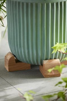 a large green planter sitting on top of a cement floor next to a potted plant