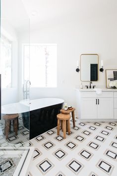 a bathroom with black and white tile flooring and a bathtub in the corner