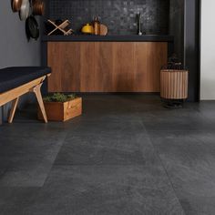 a kitchen with black tile floors and wooden cabinetry on the wall, along with potted plants