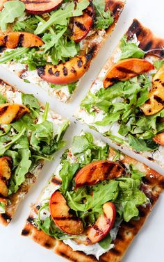 four slices of grilled peach and arugula flatbread pizza on a white surface