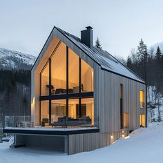 the house is surrounded by snow and lit up with lights on it's windows