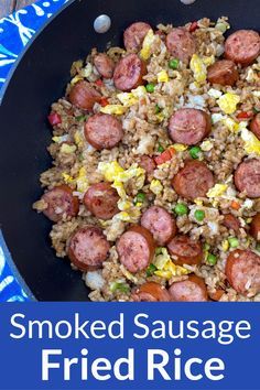 a skillet filled with fried sausage and rice on top of a blue table cloth