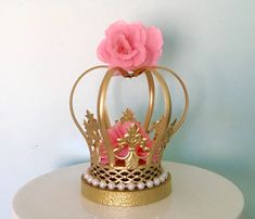 a gold crown with a pink flower on it sitting on top of a white table