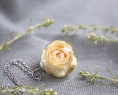 This white rose necklace is part of my white flower jewelry collection. Imagine this unique creation in your hands: A real rose flower necklace as the best bridesmaid gift or as a personalized gift. This dainty rose necklace is possibly the most original bridesmaid flower necklace. Its elegance and beauty make it perfect for formal occasions (over dark colors) or informal (over pastel or light colors). This white rose necklace comes with a hypoallergenic stainless steel collar. The resin provide Elegant White Necklace With Pressed Flowers, Elegant White Pressed Flower Necklace, White Jewelry With Rose Design As Gift, White Jewelry With Rose Design For Gift, Rose Gold Flower Necklace For Wedding, White Rose Design Necklace As Gift, White Rose Design Necklace For Gift, Rose Gold Round Flower Necklace For Wedding, Delicate Rose Necklace For Gift