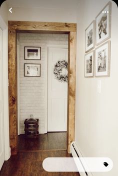 a hallway with pictures on the wall and a white door in front of it that leads to another room