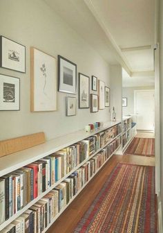 a long bookshelf filled with lots of books on top of a wooden floor