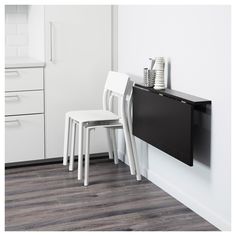 two white chairs and a black table in a room with drawers on the wall next to each other