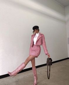 a woman in a pink suit and hat holding an umbrella while posing for the camera