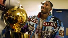 a man standing next to two golden basketballs in a locker room with other items