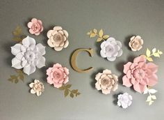 the wall is decorated with paper flowers and gold letters that spell c, which are cut out of cardboard