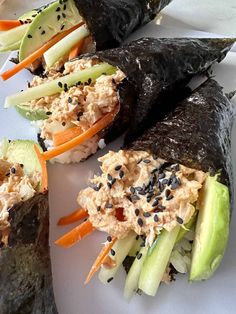 several sushi rolls on a white plate with carrots, celery and black sesame seeds