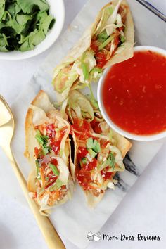 some tacos are sitting on a plate next to a bowl of sauce