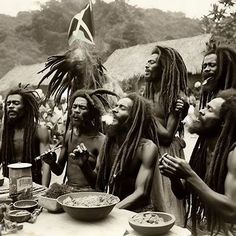 a group of men with dreadlocks standing around a table full of food and drinks