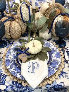 a blue and white table setting with pumpkins