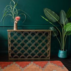 two potted plants sit on top of a table next to a rug and vase