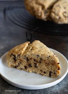 a white plate topped with a piece of cake next to a cooling rack filled with cookies