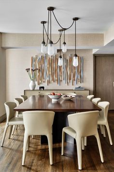 a dining room table with six chairs and an art piece on the wall behind it