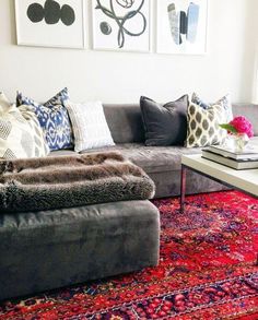 a living room filled with lots of furniture and pillows on top of a red rug