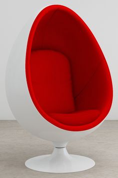 a red and white ball chair sitting on top of a wooden floor next to a wall