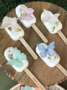 four butterfly shaped lollipops sitting on top of a wooden table