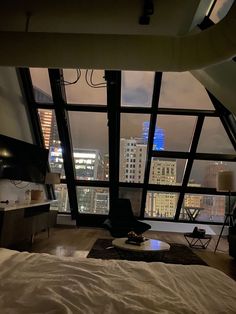 a bedroom with large windows and a view of the city from it's bed