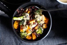 a bowl filled with broccoli, cheese and other food on top of a table