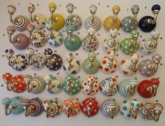 a collection of colorful glass knobs and pulls on a white wall with polka dots