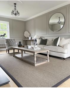 a living room filled with furniture and a mirror on the wall above it's coffee table