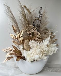 a white bowl filled with lots of different types of flowers and plants on top of a table