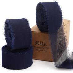 two rolls of blue cloth sitting on top of a cardboard box next to each other