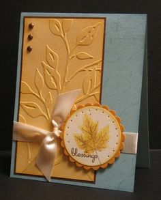 a handmade card with an autumn leaf on the front and ribbon at the bottom