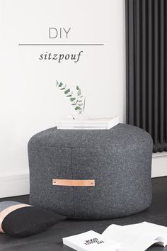 a grey ottoman sitting on top of a black floor next to a radiator